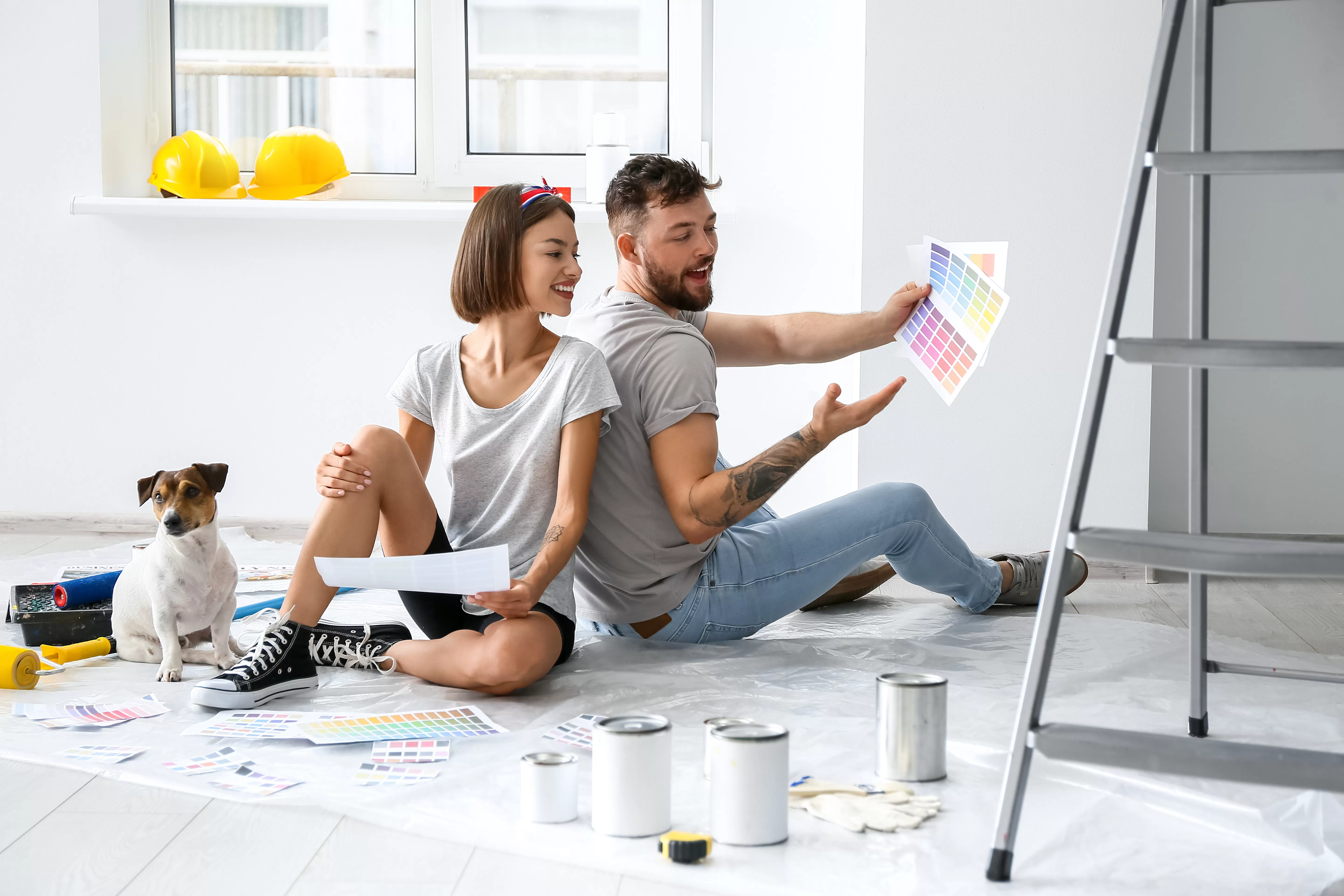 Young couple with cute dog look at paint samples as they plan the design of their new house.